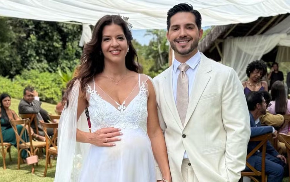 Mariana Santos está vestida de noiva ao lado de Igor Cosso em cena de casamento na novela Mania de Você, da Globo
