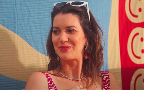 Nathalia Dill em entrevista ao canal GiMi, co mroupa de praia e óculos de sol na cabeça