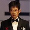 Lee Jung-jae tem expressão séria em cena de Round 6; ele veste um terno preto e tem o rosto levemente ensanguentado