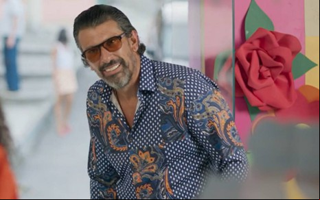 O ator Milhem Cortaz sorrindo em cena de Volta por Cima