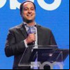 Paulo Marinho sorri e segura microfone com o logo da Globo em evento