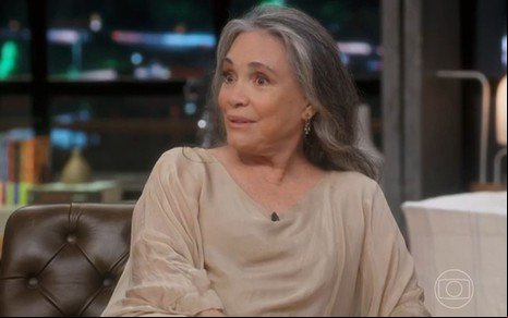 Regina Duarte com expressão séria e blusa bege no cenário do Conversa com Bial