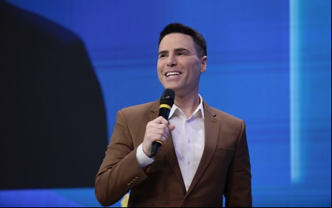Luiz Bacci fala sorridente em microfone durante evento de apresentação da nova grade do SBT